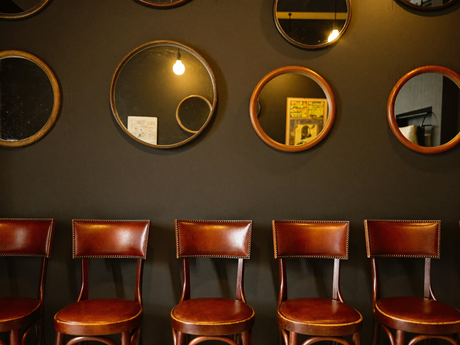 Fauteuils en cuir face aux miroirs ronds rétro-éclairés